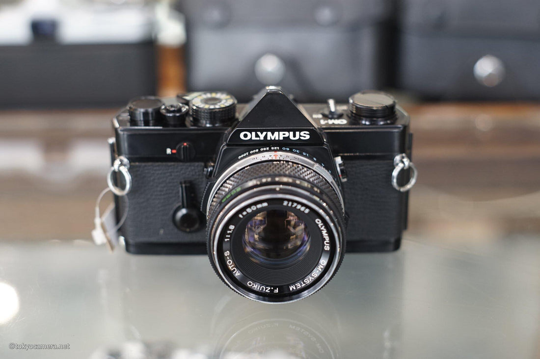 Olympus camera with F.Zuiko 50mm F1.8 lens, showcasing classic design and compact features.