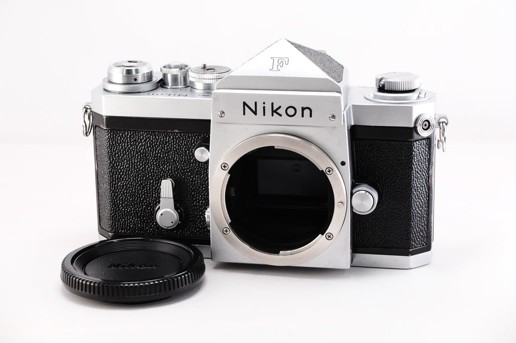 Nikon F film camera body with lens mount and cap, featuring a classic silver and black design.